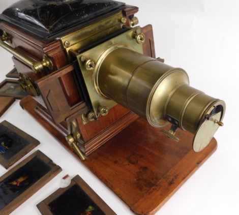 A late Victorian brass, mahogany and toleware magic lantern, stamped D. Noakes and Sons, Greenwich, London, on a rectangular base and various slides, including a man riding a pig.