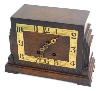 A mid 20thC Art Deco oak cased mantel clock, with brass pierced numerals, with stepped sides, on rectangular base, with eight day movement striking on the hour and half hours, 21cm high.