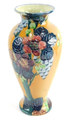 A 20thC TF&S Limited Trogonware pottery vase, sgrafitto decorated with flowers, on a yellow ground, impressed marks beneath, 33cm high.