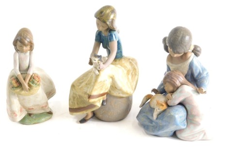 Three matt finish Lladro figures, number 2169, girl holding kitten, 24cm high, another girl holding basket, and two girls and kitten, printed marks beneath. (3)