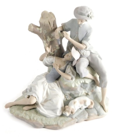 A Lladro matt finish figure of courting couple aside tree bough, printed marks beneath, 29cm high.