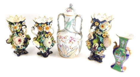 A Coalbrookdale style porcelain three piece vase set, each profusely decorated with raised flowers on a blue and gilt lined ground, one 29cm high, the other smaller, unmarked, a further vase, and Oriental lidded two handled jar. (5)