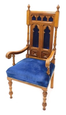 A Victorian gothic oak throne chair, with acorn finials, upholstered back and seat in blue velvet, on turned front legs with heavy scroll arms and Gothic style back panels, 118cm high.