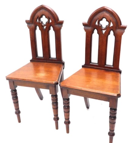 A pair of late 19thC mahogany Gothic hall chairs, with pierced mitre backs, canted seats and turned front legs, 94cm high.