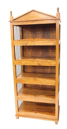 An Eastern hardwood bookcase, with a fixed architectural pediment, above open shelves with turned metal sides, on block feet, 185cm high, 74cm wide, 42cm deep.