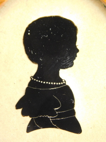 A 19thC silhouette of a girl, 7cm x 5cm, in bird's eye maple frame.