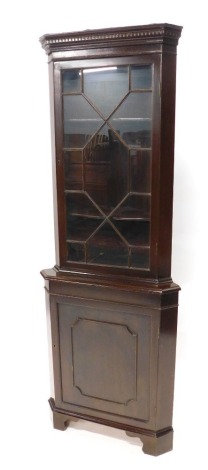 A mahogany standing corner cabinet in George III style, the dentil cornice raised above an astragal glazed doors, enclosing shaped shelves, the base with a further panelled cupboard door on bracket feet, 182cm high, 59cm wide.