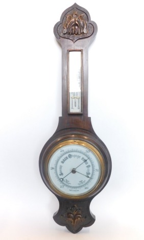 A 20thC two dial oak cased banjo barometer thermometer, with 16cm diameter main dial in a heavily carved case set with scrolls and flowers, 77cm high.