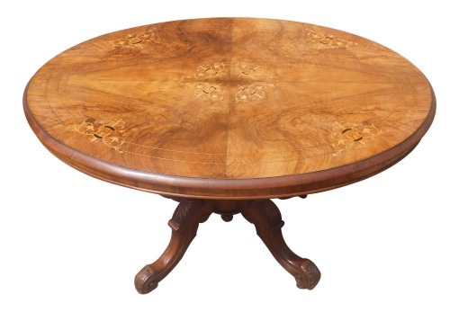 A Victorian walnut and inlaid loo table, the tilt top on a set of four heavily carved supports terminating in scroll feet with castors, 73cm high, 105cm wide, 85cm deep.