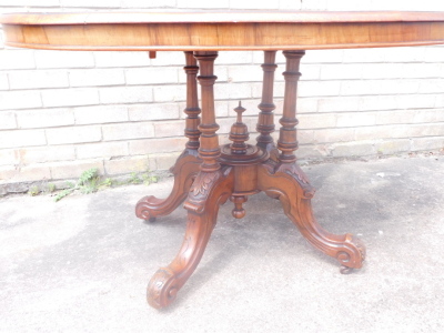 A Victorian walnut and inlaid loo table, the tilt top on a set of four heavily carved supports terminating in scroll feet with castors, 73cm high, 105cm wide, 85cm deep. - 2