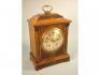 An Edwardian oak bracket clock with a silvered dial in a carved case