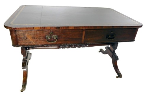 A George IV rosewood writing table, the rectangular top with black and gilt tooled leather inset, above two frieze drawers, each with fitted division and Bramah locks, on leaf and scroll carved end supports and sabre legs, with brass castors, 75cm high, 1