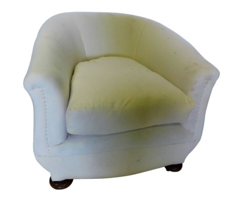 An early 20thC tub shaped armchair, on bun feet with castors.