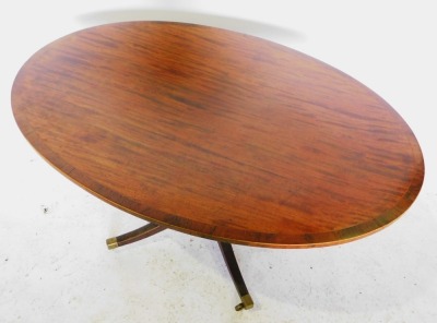An early 19thC flamed mahogany oval breakfast table, with rosewood crossbaned top, plain taper column and reeded legs with brass cap castors, 70cm high, the top 137cm x 97cm - 2