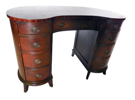 A mahogany kidney shaped desk or dressing table, with an arrangement of nine drawers, each with oval metal handles, on splayed feet, 77cm high, 114cm wide, 56cm deep.