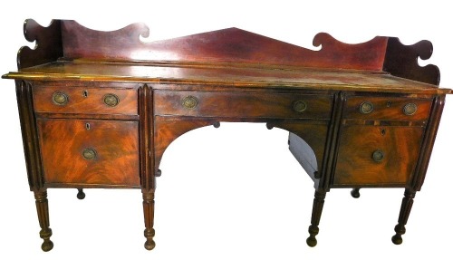 An early 19thC mahogany sideboard, the top with a shaped raised gallery and a moulded edge, above an arrangement of three frieze drawers and two doors, each with oval brass drop handles cast with urn, on turned reeded legs, 110cm high, 201cm wide, 62cm de
