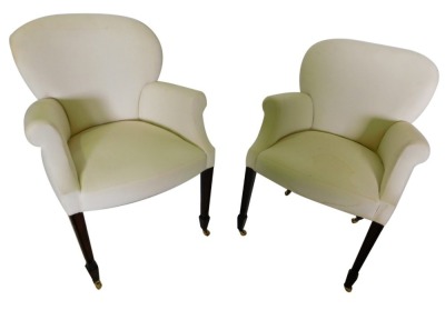 A pair of mahogany armchairs, each with a rounded back, shaped arm, and a padded seat, on channelled square tapering legs, with brass castors.