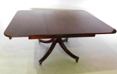 A mahogany extending dining table, the rectangular top with a reeded edge and rounded corners, opening to reveal a spring loaded leaf, on turned legs and reeded sabre legs, and brass castors, 72cm high, the top 106cm x 150cm. - 2