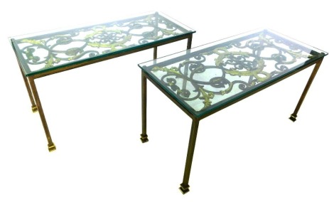 A pair of parcel gilt metal coffee tables, each with a rectangular glass top, above an elaborate scroll cast panel decorated with dragons, leaves, etc., on plain supports, with stepped feet, 53cm high, 100cm wide, 44cm deep.