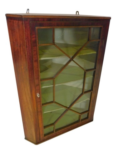 An early 19thC mahogany and chequer banded hanging corner cabinet, with an astragal glazed door and painted interior, 101cm high, 75cm wide.