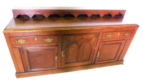 A late 19thC oak dresser, the top with a raised back and moulded edge, above two drawers, two panelled doors flanking a central larger door with Gothic style arch, on a plinth, 95cm high, 101cm wide.