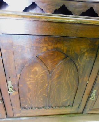 A late 19thC oak dresser, the top with a raised back and moulded edge, above two drawers, two panelled doors flanking a central larger door with Gothic style arch, on a plinth, 95cm high, 101cm wide. - 2