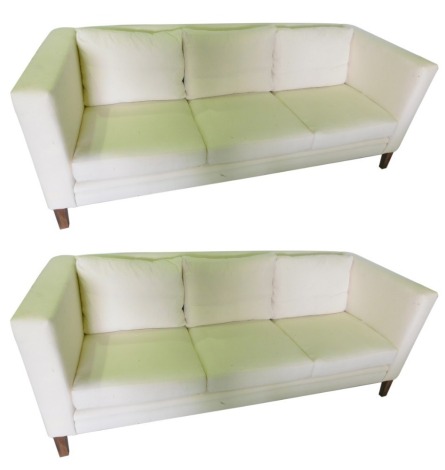 A pair of three seat sofas in George III style, each with square tapering hardwood legs, upholstered in white calico, 112cm wide. The upholstery in this lot does not comply with the 1988 (Fire & Fire Furnishing) Regulations, unless sold to a known exporte