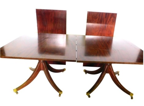 A mahogany twin pillar dining table, the rectangular top with rounded corners, on a turned column and sabre legs, with brass castors, two loose leaves, 76cm high, 122cm wide, 312cm long.