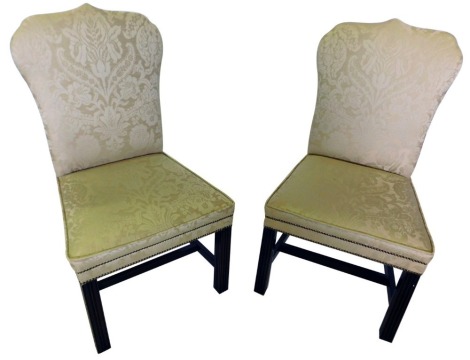 A pair of mahogany chairs in George III style, each with a shield shaped back and a padded seat, upholstered in cream Damask fabric, on reeded legs, with H stretcher.