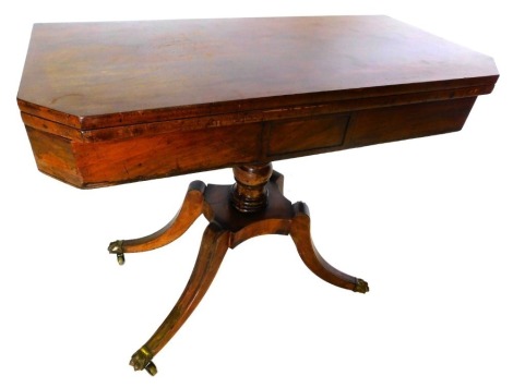 A Regency mahogany and ebony strung card table, the rectangular top with canted corners, green baize lined, above a plain frieze with central rectangular panel, on turned column, concave platform, and sabre legs with brass castors, 73cm high, 90cm wide, 4