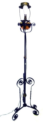 An early 20thC wrought iron and copper adjustable floor lamp, with oil reservoir, on triform base, converted to electricity.