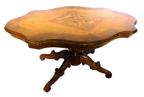 A late 20thC Italian walnut and marquetry coffee table, with a shaped quarter veneered top, on a carved turned column and four scrolling legs, 53cm high, 101cm wide, 62cm deep.