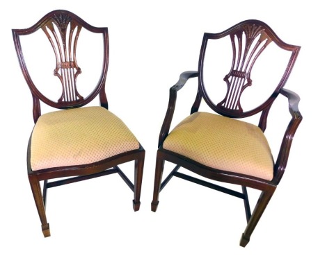 A set of eight mahogany dining chairs, in George III style, each with a shield shaped back, carved with wheat ears, and a pierced splat, a drop in seat, on square tapering legs, two with arms. The upholstery in this lot does not comply with the 1988 (Fire