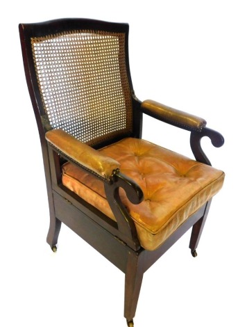 A 19thC Carter's mahogany commode armchair, with a caned back, hinged sides with brown leather pads, a brown leather buttoned cushion, above a cupboard recess inset with a Carter's Invalid Appliances ceramic bowl, on square tapering legs, ivorine makers p