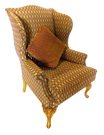 A gilt wingback chair in George III style, upholstered in geometric pattern fabric, on carved cabriole legs.