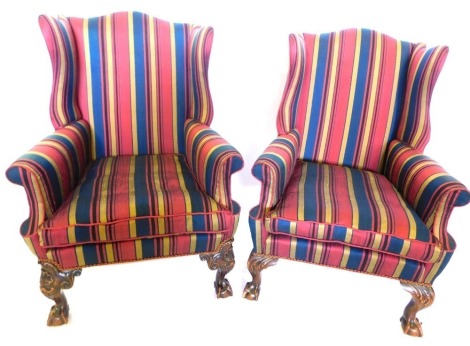 A mahogany wingback chair in George III style, upholstered in red, gold, blue and black striped fabric, on shell and scroll carved cabriole legs, with ball and claw feet, and a similar chair with matching upholstery. (2).