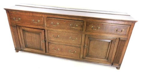 An oak and mahogany cross banded dresser in 18thC style, of plain form with arrangement of five drawers and two panelled doors, 185cm wide. AUCTIONEER ANNOUNCE: New description 'Georgian oak and mahogany cross banded dresser, now with plate rack top.'