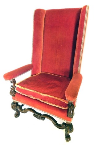 A 19thC Continental wingback open armchair, upholstered in red velvet, with scroll carved arm supports, stretcher and legs.