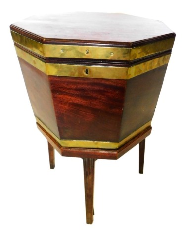 A George III mahogany and brass bound octagonal cellarette, the hinged lid enclosing a metal lined interior, the base with brass side hinges, on a plain stem, with square tapering legs, 69cm high, 49cm wide.