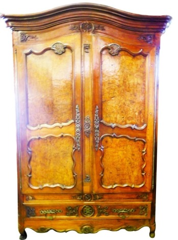 A 19thC French provincial walnut armoire, with swept moulded cornice, the carved frieze with a basket, scroll and foliage decoration, the hanging compartment enclosed by two arched doors, with burr walnut panels, fitted a drawer to base with a shaped and 