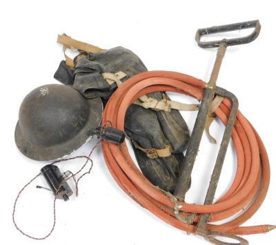 A World War II ARP tin helmet, anti gas, over boots, and stirrup pump.