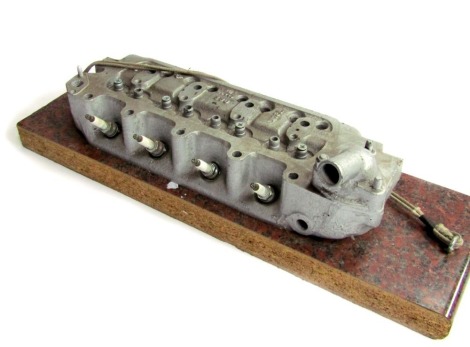 A vintage car cylinder head, No 18L, UG840338, on plinth, the unit 43cm wide, the base 60cm wide.