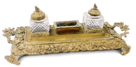 A Continental gilt metal inkstand, cast overall with flowers and leaves, the top mounted with two cut glass inkwells, 45cm wide.