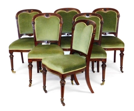 A set of six early Victorian mahogany dining chairs, each with a balloon shaped back, green leather back and seat on turned tapering legs with brass castors.