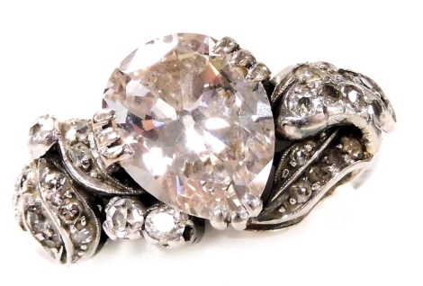 An Art Deco diamond and platinum ring, the central pear shaped diamond claw set at an angle with scrolling shoulders, set with brilliant cut and old cut diamonds, in a leaf and berry design, pear shaped diamond approximately 2.7ct, size N, 7.1g.