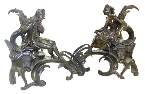 A pair of late 19thC French bronze chenets, of eighteenth century form, cast with a seated lady, and a gallant playing a flute, raised on a rococo foliate scroll base, 28cm wide.