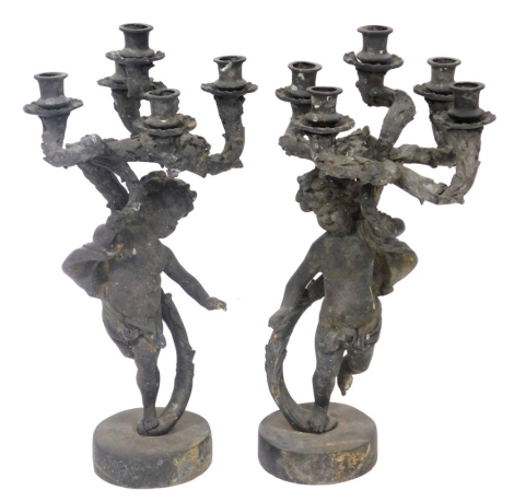 A pair of late 19thC Continental patinated metal five branch candelabra, modelled as putti, raised on circular bases, 66cm high.