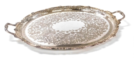 A Victorian silver plated twin handled tray, of oval form, engraved centrally with flowers and foliate scrolls, within a raised border, pierced and embossed with flowers and foliate scrolls, 76cm wide.