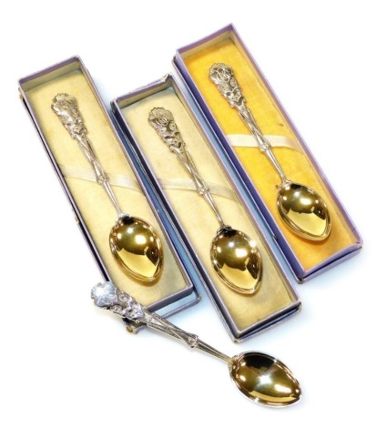 A set of four George V silver golfing related teaspoons, each handle cast with golf clubs and balls, monogram engraved, silver gilt bowls, Vaughton & Sons, Birmingham 1925,1927 and 1928, 2.45oz, three boxed.