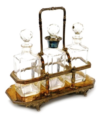 A late Victorian silver plated tantalus, with three cut glass decanters, the central decanter with a silver plated collar, each 24cm high, the stand raised on four scroll work feet, 31cm high.